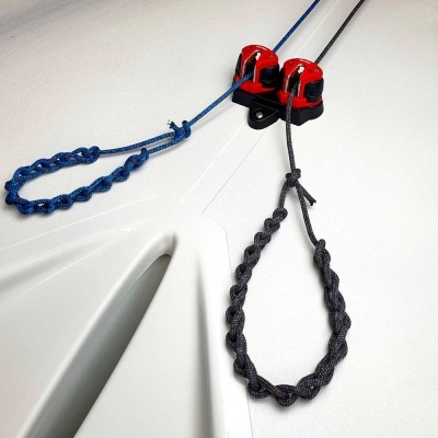 Polias vermelhas e cordas trançadas num casco de embarcação branco