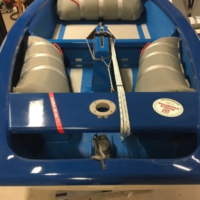 Barco pequeno azul com almofadas infláveis cinzentas e etiquetas num armazém