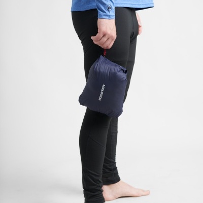 Pessoa com calças pretas e camisola azul segurando embalagem azul Robustek descalço em fundo branco