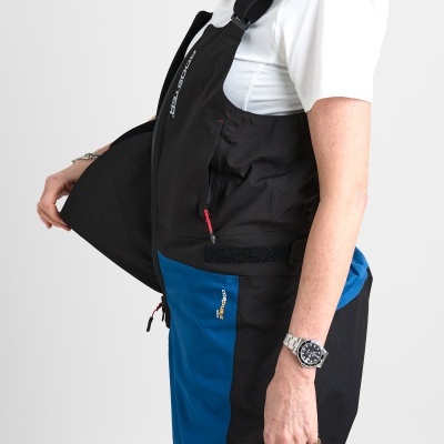 Macacão preto e azul com alças e bolso lateral, usado por pessoa veste t-shirt branca