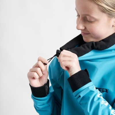 Pessoa com casaco azul claro com detalhes pretos ajustando cordão na gola