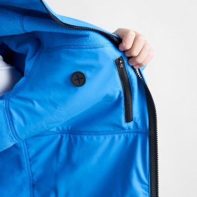 Casaco azul com bolso interno e fecho preto aberto na mão de uma pessoa