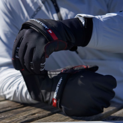 Luvas pretas ROOSTER com detalhes vermelhos e brancos usadas por pessoa com jaqueta cinza