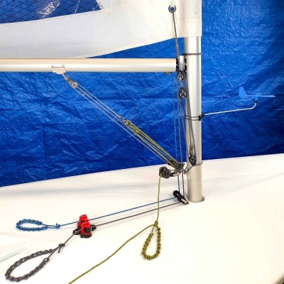 Mastro de veleiro pequeno com cabos coloridos e vela branca em fundo azul