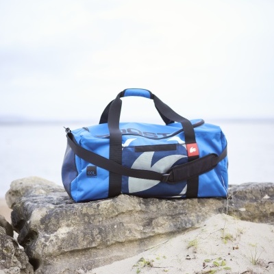 Mala de viagem azul com alças pretas sobre uma pedra na praia