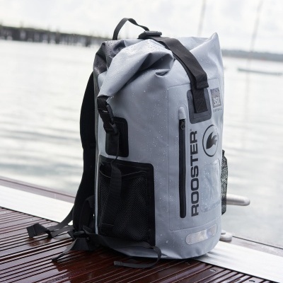 Mochila impermeável cinzenta com fecho enrolável e texto ROOSTER preta junto à água