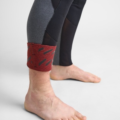 Pernas com calças justas cinzentas e pretas e faixa vermelha no tornozelo