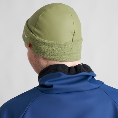 Gorro verde com aba felpuda e casaco azul visto de trás.