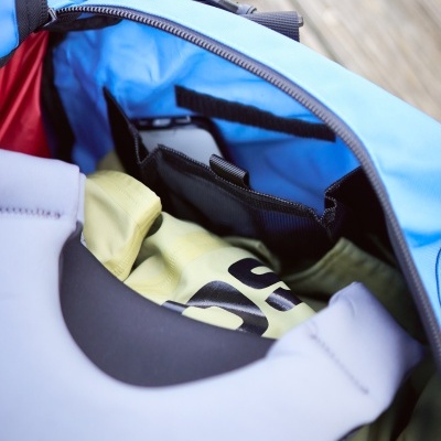 Interior de mochila azul com colete amarelo e colete salva-vidas branco com texto ROOSTER