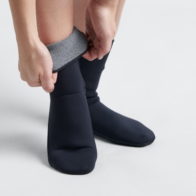 Pessoa calçando meias pretas com parte superior cinza em fundo branco