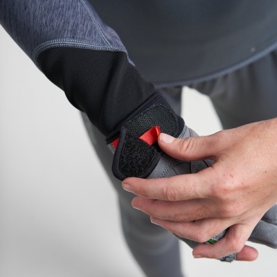 Mãos a colocar uma luva desportiva cinzenta com detalhe preto e vermelha