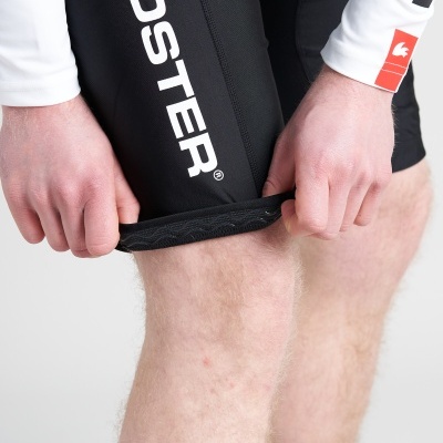 Calção de ciclismo preto com logótipos brancos e punho texturizado sendo esticado por mãos