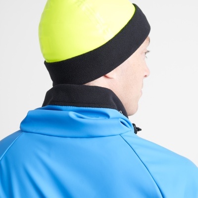 Gorro amarelo fluorescente e preto usado por pessoa com casaco azul vista de costas