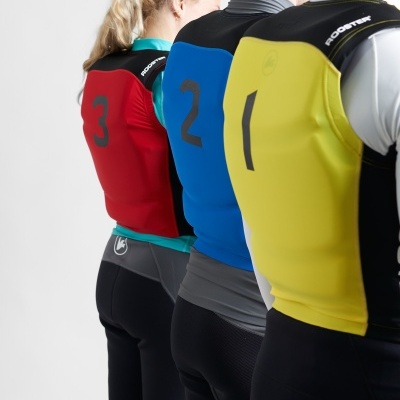 Três pessoas de costas com coletes de proteção coloridos e numerados.