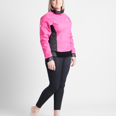 Mulher vestindo camisa rosa e preta com calças pretas e posando em fundo branco