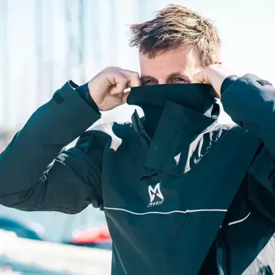 Homem com casaco azul escuro com logótipo MUSTO num cenário de marina