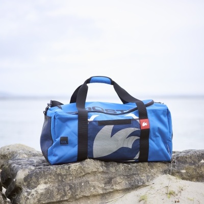 Saco desportivo azul com alças pretas sobre rocha na praia