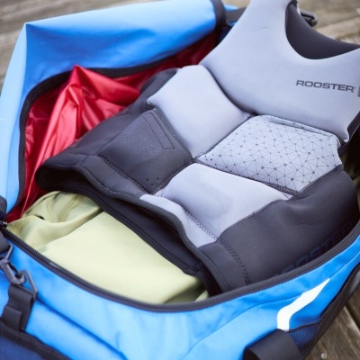 Mala de desporto azul aberta com roupa desportiva dentro sobre madeira