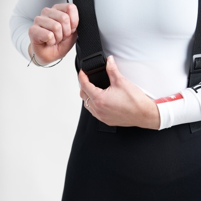 Pessoa segurando alça preta ajustável com camisola branca e peça inferior preta