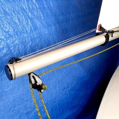 Barra de vela branca com cordas e polia preta contra fundo azul texturado.