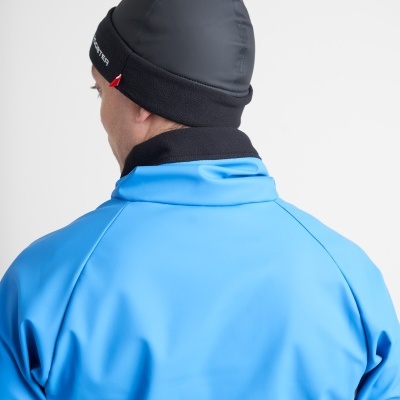 Homem de costas com casaco azul e gorro preto com etiqueta vermelha