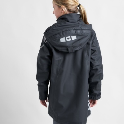 Casaco impermeável preto com capuz em criança, detalhes brancos e fechos ajustáveis.