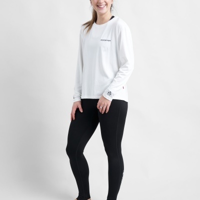 Mulher com t-shirt branca de manga comprida e calças pretas justas em fundo branco