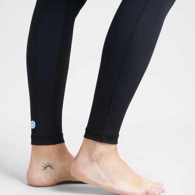 Pessoa a usar leggings pretas justas com logótipo azul perto do tornozelo à esquerda