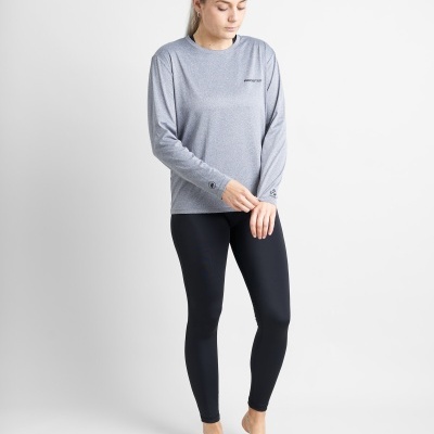 Mulher com camisola de manga comprida cinzenta e legging preta em fundo branco.