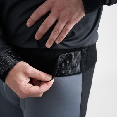 Pessoa a ajustar faixa preta com fecho adesivo em roupa cinzenta e preta