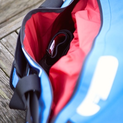 Mala desportiva azul com interior vermelho e objeto preto no interior