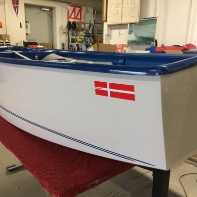 Barco pequeno branco e azul com bandeira da Dinamarca em oficina
