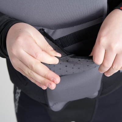 Pessoa vestindo equipamento de neoprene cinza e preto com texto 'ROOST' segurando uma aba de velcro.