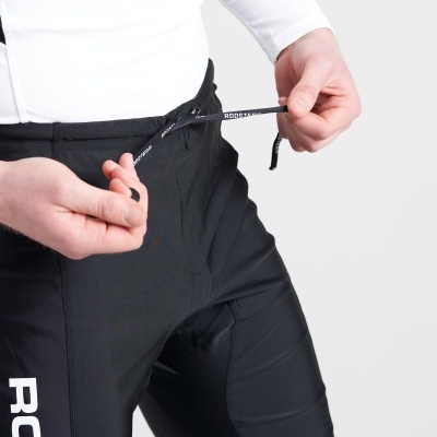 Calças desportivas pretas com cordão de aperto e texto 'ROOS' em fundo branco