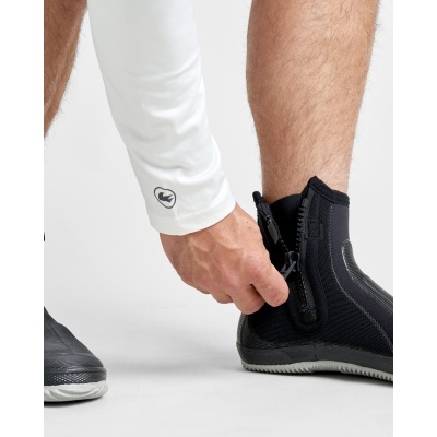 Pessoa a calçar botins pretos com fecho e luva branca com símbolo preto