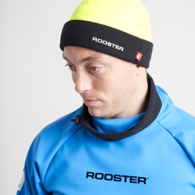 Homem com gorro amarelo e aba preta com escrito ROOSTER e camisa azul com palavra ROOSTER
