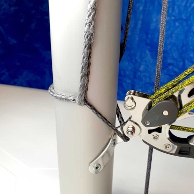 Corda e sistema de polias metálico prateado ligado a vela branca com fundo azul