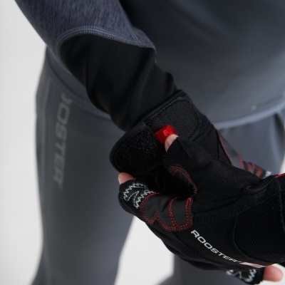 Luva desportiva preta com costuras vermelhas e texto ROOSTER, ajustada numa mão com roupa desportiva cinza