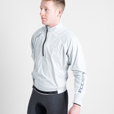 Homem com casaco cinza claro e calças pretas justas em fundo branco.