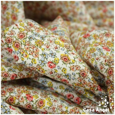 Tecido floral colorido sobre fundo branco com padrão detalhado de flores pequenas.