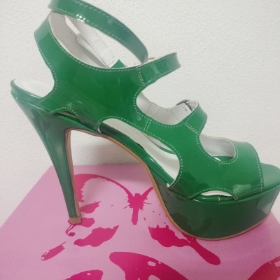Sandália verde de salto alto e plataforma sobre caixa rosa com borboletas