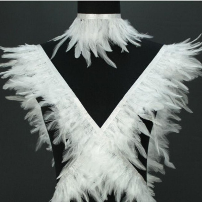 Vestido com penas brancas sobre manequim preto e fundo cinzento