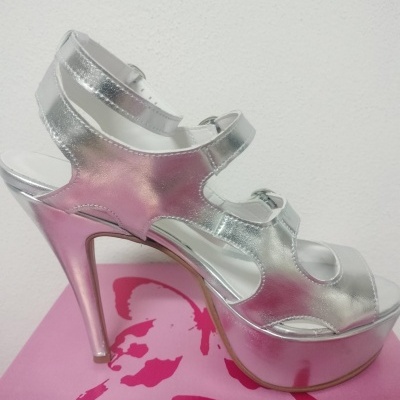 Sandália prateada de salto alto com tiras ajustáveis sobre caixa cor-de-rosa com borboleta vermelha