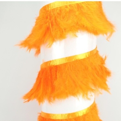 Faixa decorativa laranja com penas e fitas douradas sobre fundo claro