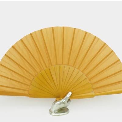 Leque amarelo sólido com estrutura de ripas sobre mão decorativa metálica prateada