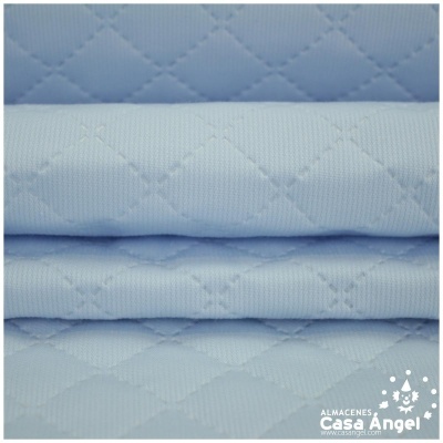Tecido azul claro acolchoado com padrão de losangos e texto 'ALMACENES Casa Ángel'