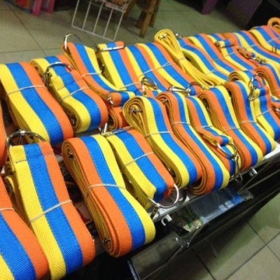 Correas de tecido tricolor com anéis metálicos sobre superfície preta