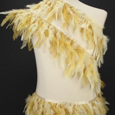 Veste e saia com penas amarelas e bege sobre manequim branco