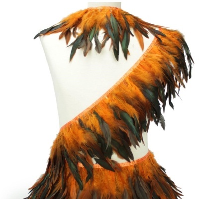 Peça com penas laranja, preto e verde em manequim branco
