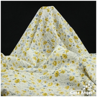 Tecido branco com padrão floral amarelo e azul dobrado sobre fundo preto